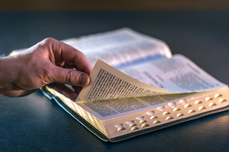 Hand resting on the pages of an open Bible